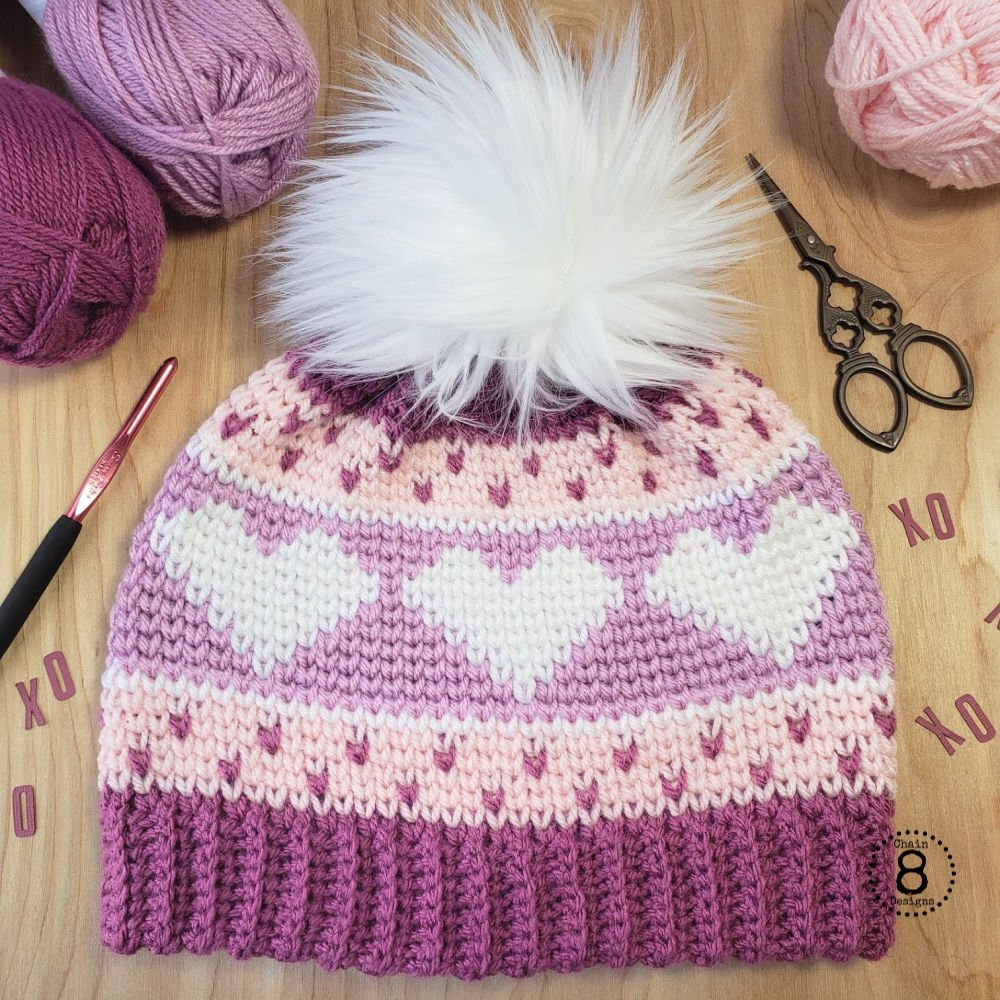 This cute crochet heart beanie is made using the waistcoat stitch (aka the knit stitch). This is an adult-sized hat. The pattern features step-by-step directions with lots of photos and a bonus full waistcoat stitch tutorial. Make one for someone you love today! #waistcoatstitch #crochethatpattern #crochetheart